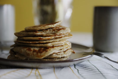 Pile of fresh pancakes placed on plate in morning in kitchen at home