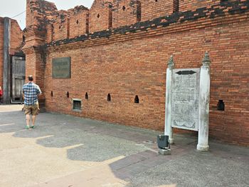 Rear view of man walking on brick wall