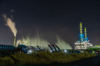 Panoramic view of illuminated factory against sky at night