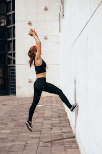 Full length of young woman exercising near wall