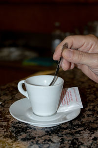 Hand holding coffee cup on table