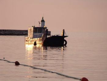 Boat in sea against clear sky during sunset