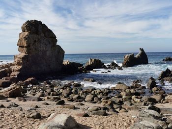 Rocks on sea shore against sky