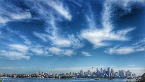 City at waterfront against cloudy sky