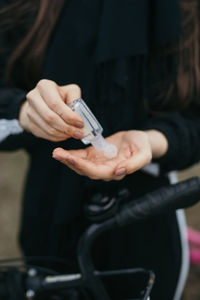 Midsection of woman taking sanitizer on hand