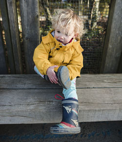 High angle view of girl looking away while sitting on wooden seat