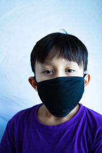 Close-up portrait of boy wearing mask against wall