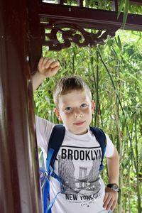 Portrait of boy standing against trees