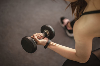 High angle view of young woman lifting dumbbell in gym