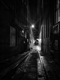 Empty street amidst buildings in city at night