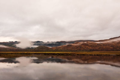 Scenic view of lake by mountains against sky