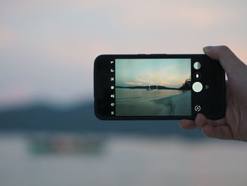 Reflection of man photographing on mobile phone