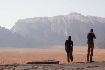 Men standing on rock against mountains