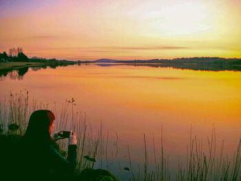 Scenic view of lake against orange sky