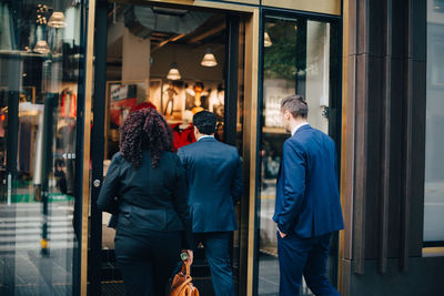 Rear view of business colleagues entering cafe in city