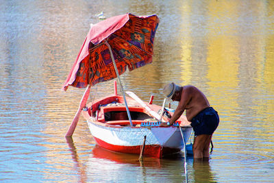 Side view of shirtless senior man with boat in lake