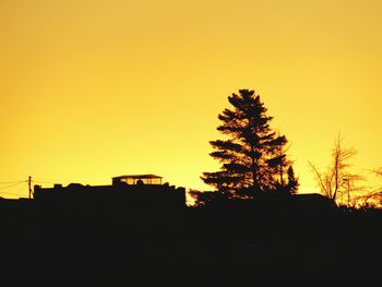 Silhouette trees against orange sky