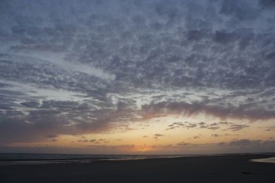 Scenic view of sea against dramatic sky during sunset