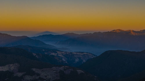 Scenic view of silhouette mountains against orange sky