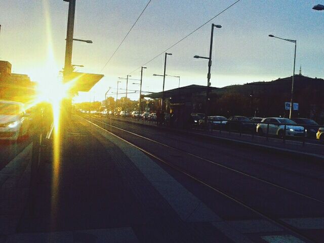 transportation, railroad track, mode of transport, railroad station platform, public transportation, sunset, rail transportation, railroad station, sky, the way forward, travel, land vehicle, car, diminishing perspective, sun, on the move, vanishing point, road, train - vehicle, sunlight