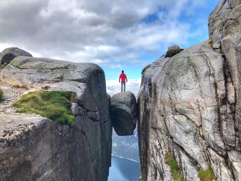 Rear view of man looking at rock formation against sky