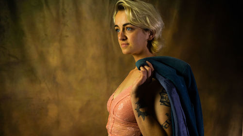 Portrait of young woman standing against wall