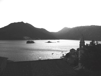 Boats in calm sea against mountain range