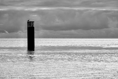 Lighthouse on sea against sky