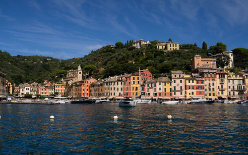 Buildings by river against sky