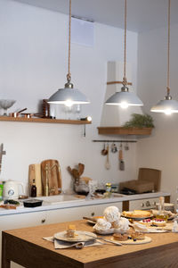 Vertical shot of a kitchen with hanging chandeliers and a table with cakes and pastries