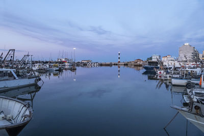 The port of cattolica with the boats and the lighthouse reflecting in the water at sunset