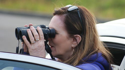 Close-up of woman looking through binoculars