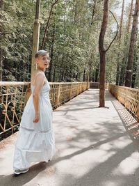 Side view of woman standing against trees