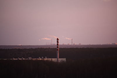 Smoke emitting from factory against sky during sunset