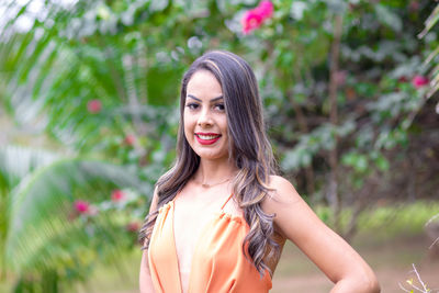 Portrait of smiling young woman standing against plants