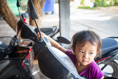 Cute girl sanding by motor scooter on street