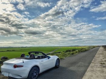 Road amidst field against sky