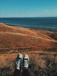 Low section of person by sea against sky