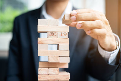 Midsection of businessman stacking toy blocks