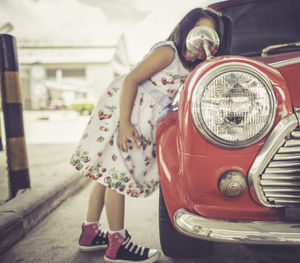 Midsection of woman with red car parked in city