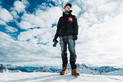 Man standing on snowcapped mountain against sky