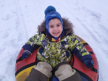 Portrait of smiling young woman sitting on snow