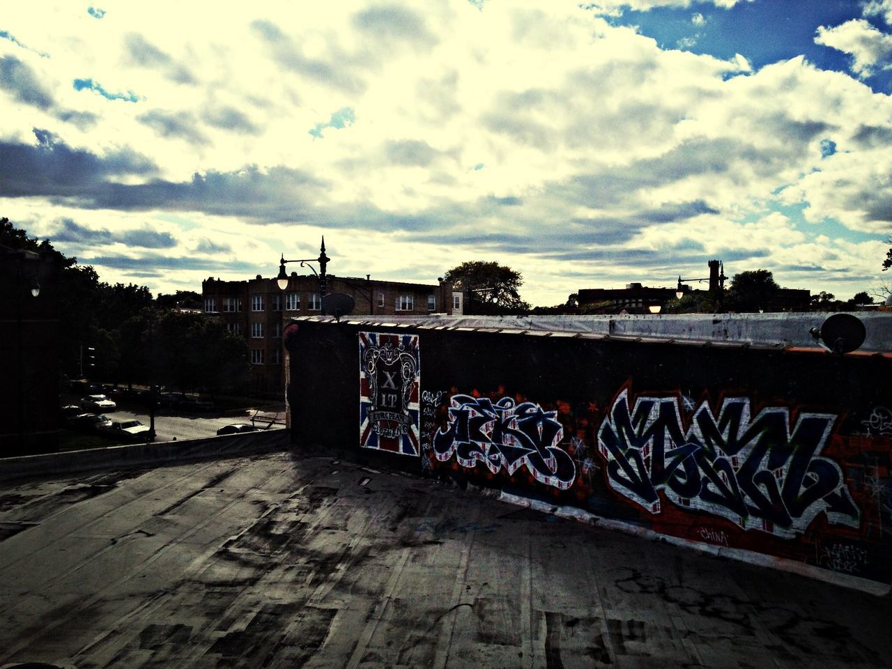 sky, built structure, architecture, text, graffiti, western script, building exterior, cloud - sky, railing, art, communication, cloud, art and craft, outdoors, wall - building feature, creativity, day, bridge - man made structure, cloudy