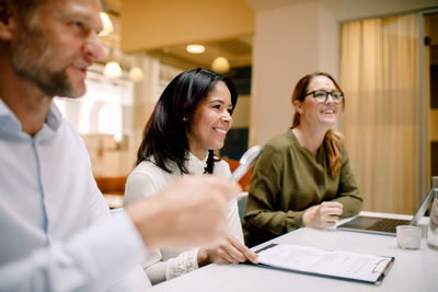 Smiling business colleagues working while sitting at conference table in office