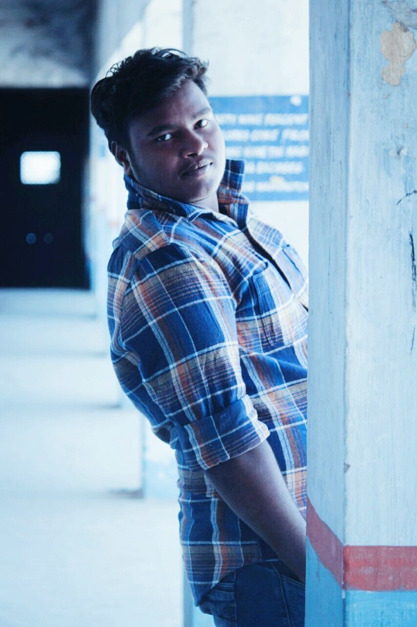 PORTRAIT OF SMILING YOUNG MAN STANDING OUTDOORS