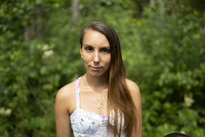 Portrait of young woman standing against plants