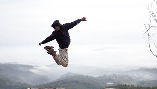 Full length of man jumping against sky