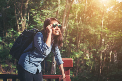 Female tourist holding sunglasses while standing at park