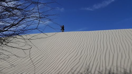 Man standing on desert land against sky