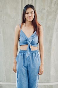 Portrait of a beautiful young woman standing against wall